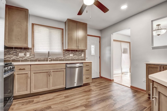 kitchen with stainless steel dishwasher, range with gas stovetop, a sink, a ceiling fan, and backsplash