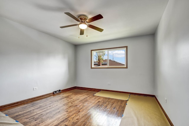 unfurnished room featuring ceiling fan, wood finished floors, and baseboards