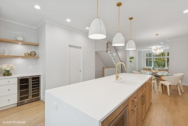 kitchen featuring beverage cooler, a sink, crown molding, light wood-type flooring, and light countertops