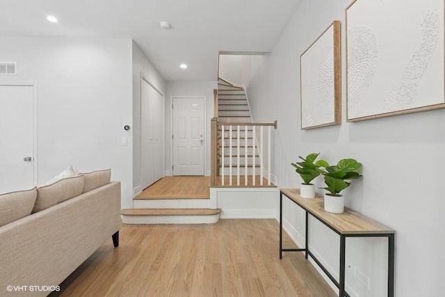 hall featuring stairs, wood finished floors, recessed lighting, and baseboards