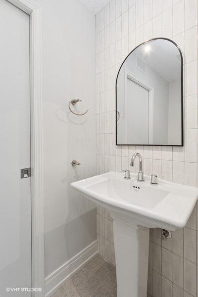 bathroom featuring tile walls, a sink, and decorative backsplash