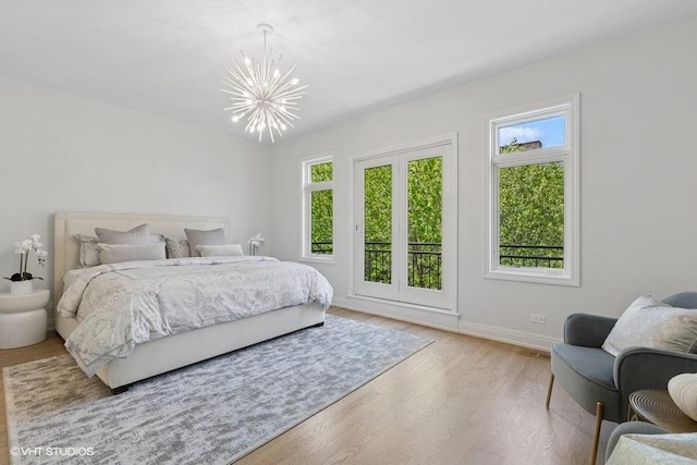 bedroom featuring a chandelier, wood finished floors, and baseboards
