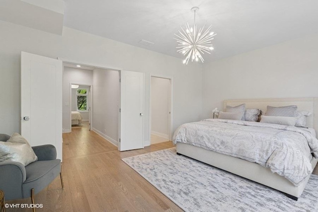 bedroom with a chandelier, light wood finished floors, and baseboards
