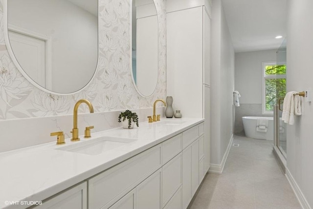 full bath featuring double vanity, a freestanding bath, baseboards, and wallpapered walls