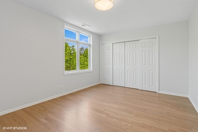 unfurnished bedroom featuring light wood-type flooring, baseboards, and a closet