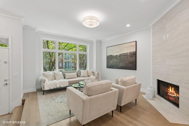 living room with ornamental molding, wood finished floors, a large fireplace, baseboards, and recessed lighting
