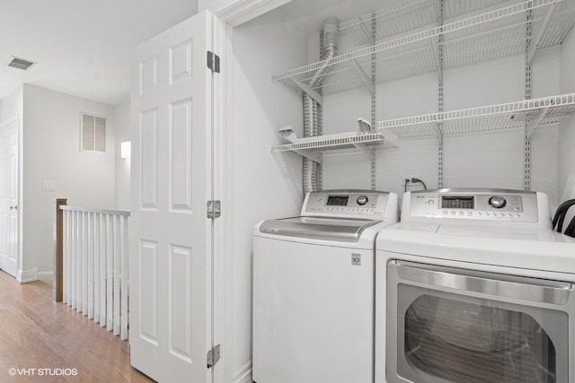 washroom featuring separate washer and dryer, light wood-type flooring, and baseboards
