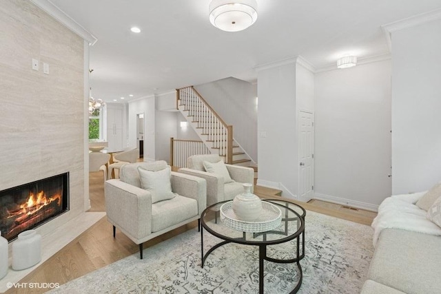 living room featuring wood finished floors, stairway, crown molding, a premium fireplace, and recessed lighting