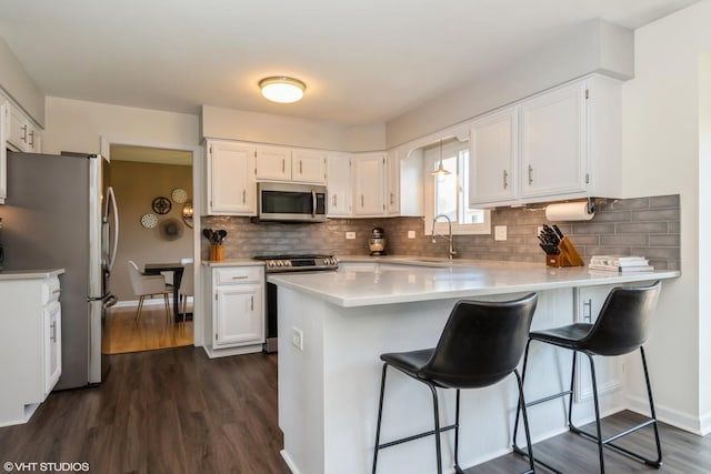 1449 Mesa Dr, Bolingbrook, IL 60490 - kitchen with appliances with stainless steel finishes, a sink, a peninsula, dark wood-style flooring, and white cabinets