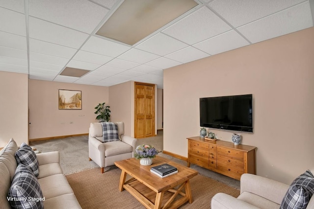 living room featuring carpet flooring, a drop ceiling, and baseboards