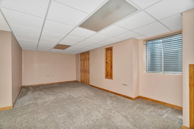 below grade area with carpet flooring, baseboards, and a drop ceiling