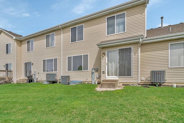 rear view of house featuring central air condition unit, a lawn, and entry steps