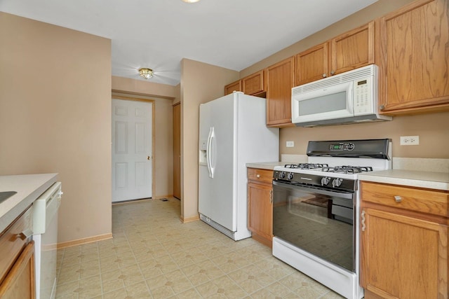 kitchen with white appliances, light countertops, baseboards, and light flooring