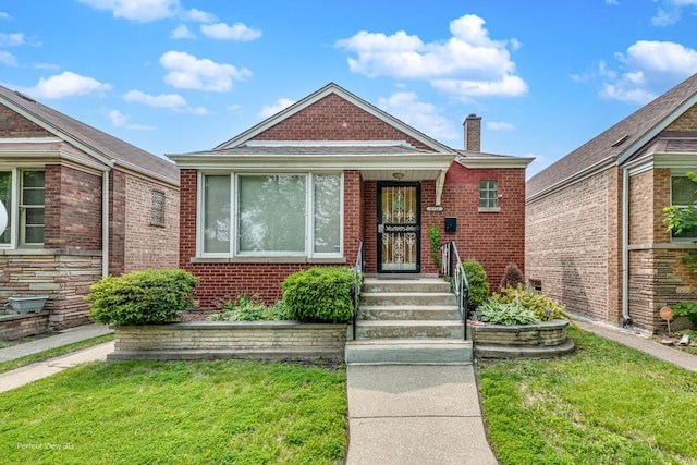 8724 S Jeffery Blvd, Chicago, IL 60617 - bungalow with brick siding, a chimney, and a front yard