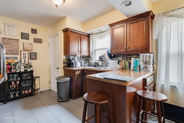 8724 S Jeffery Blvd, Chicago, IL 60617 - kitchen with a breakfast bar, a peninsula, decorative backsplash, light tile patterned floors, and light countertops