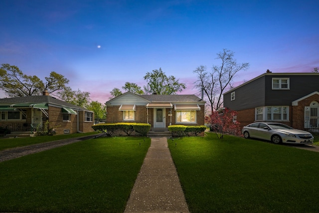 view of front of house with a yard and brick siding