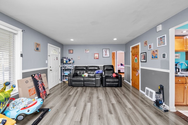 living area with recessed lighting, arched walkways, light wood-style floors, and baseboards