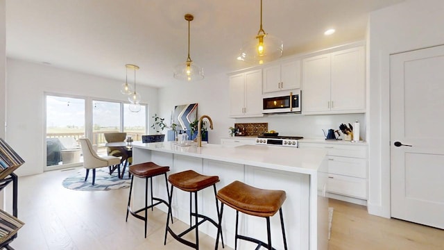 3133 Palmer Dr, Champaign, IL 61822 - kitchen with white microwave, light wood-style flooring, range, a kitchen bar, and recessed lighting