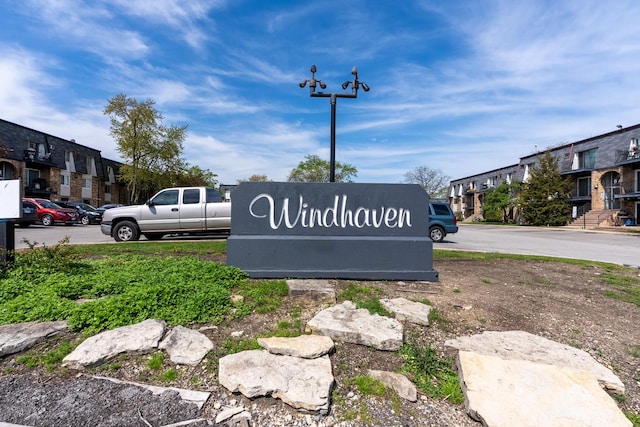 community / neighborhood sign with a residential view and uncovered parking