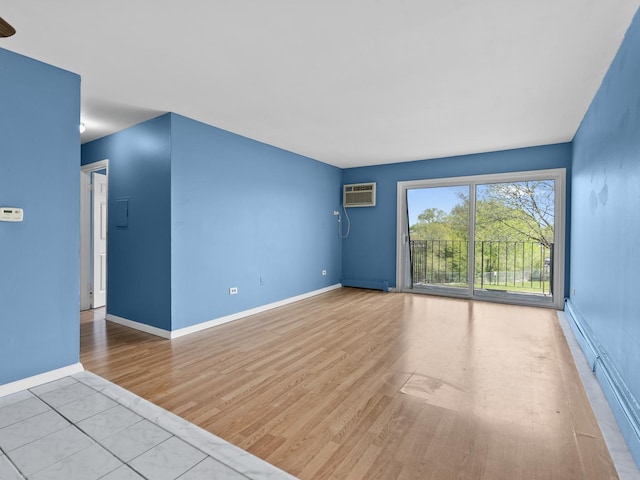 unfurnished living room with a wall unit AC, wood finished floors, baseboards, and baseboard heating