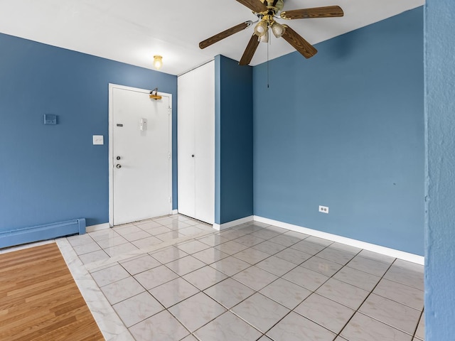 spare room featuring ceiling fan, baseboards, and a baseboard heating unit