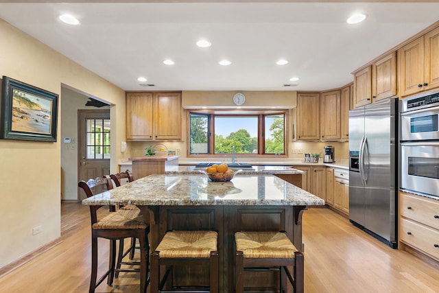 660 Plum Tree Dr, Barrington Hills, IL 60010 - kitchen with appliances with stainless steel finishes, a kitchen bar, light wood-style flooring, recessed lighting, and light stone countertops