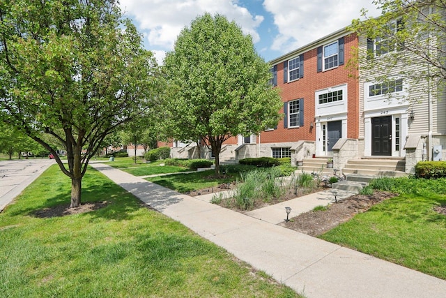 multi unit property featuring entry steps, a front lawn, and brick siding