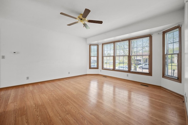 spare room with healthy amount of natural light, light wood-style floors, baseboards, and a ceiling fan