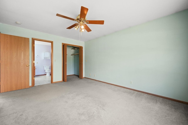 unfurnished bedroom featuring light colored carpet, baseboards, a closet, ensuite bath, and ceiling fan