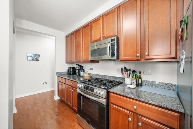 1160 S Michigan Ave Unit 1005, Chicago, IL 60605 - kitchen featuring appliances with stainless steel finishes, baseboards, dark stone counters, wood finished floors, and brown cabinetry