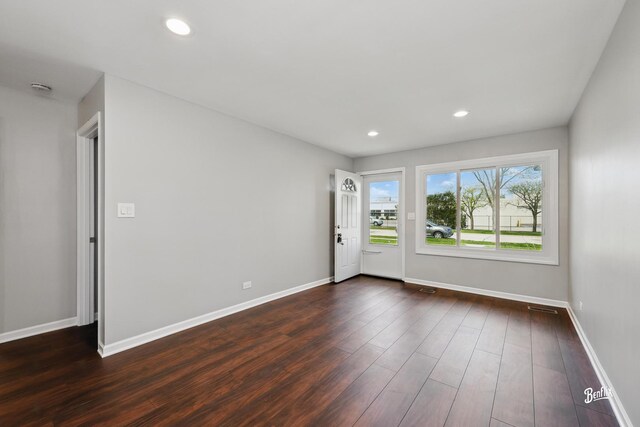 empty room with dark wood finished floors, baseboards, and recessed lighting