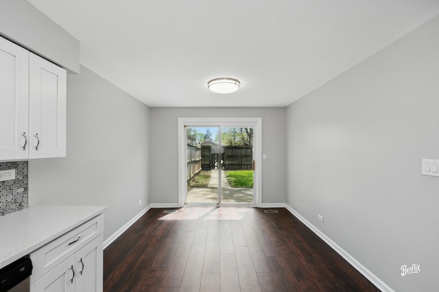 unfurnished dining area featuring dark wood-type flooring and baseboards
