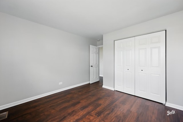 unfurnished bedroom featuring dark wood-style floors, baseboards, and a closet