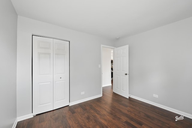 unfurnished bedroom featuring dark wood finished floors, baseboards, and a closet