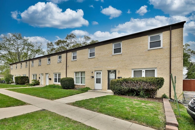 multi unit property featuring a front lawn and brick siding