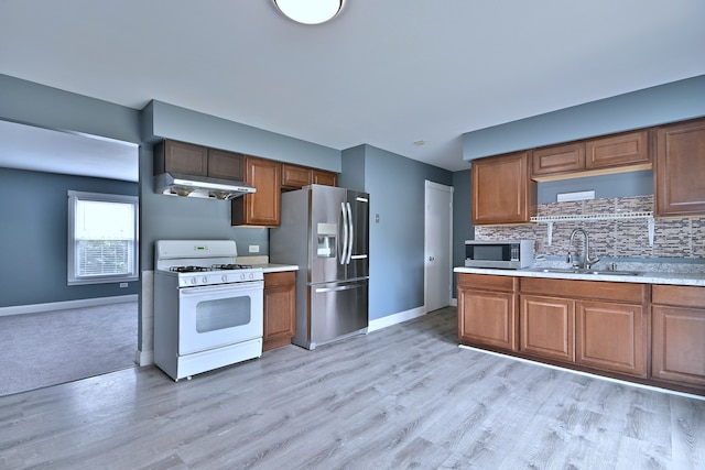 kitchen featuring appliances with stainless steel finishes, a sink, under cabinet range hood, and light countertops