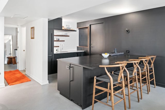kitchen featuring a sink, open shelves, a kitchen breakfast bar, modern cabinets, and finished concrete flooring