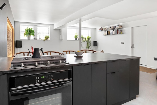 kitchen featuring oven, dark countertops, stainless steel gas stovetop, modern cabinets, and healthy amount of natural light