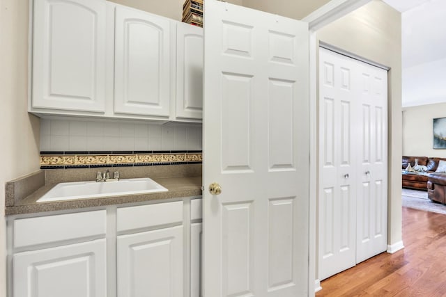 bathroom with a sink, backsplash, and wood finished floors