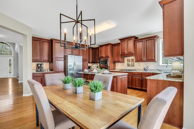 dining area featuring a chandelier, light wood finished floors, plenty of natural light, and baseboards