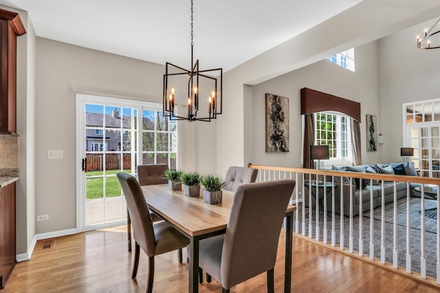 dining space with a chandelier, light wood finished floors, and baseboards