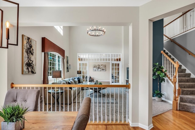 entrance foyer with a chandelier, wood finished floors, stairway, a high ceiling, and baseboards