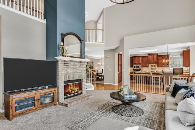living room featuring a towering ceiling, a brick fireplace, a chandelier, and baseboards