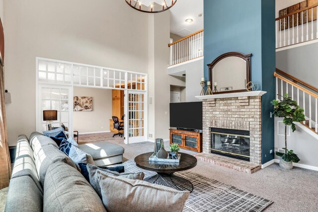 living area featuring a towering ceiling, carpet, french doors, baseboards, and a fireplace
