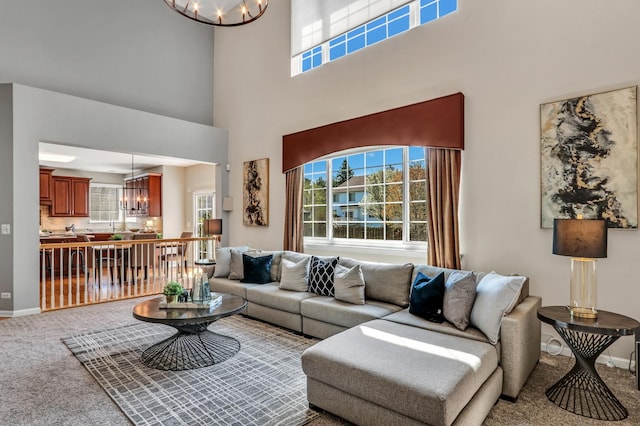 living area with a chandelier, carpet flooring, a towering ceiling, and baseboards