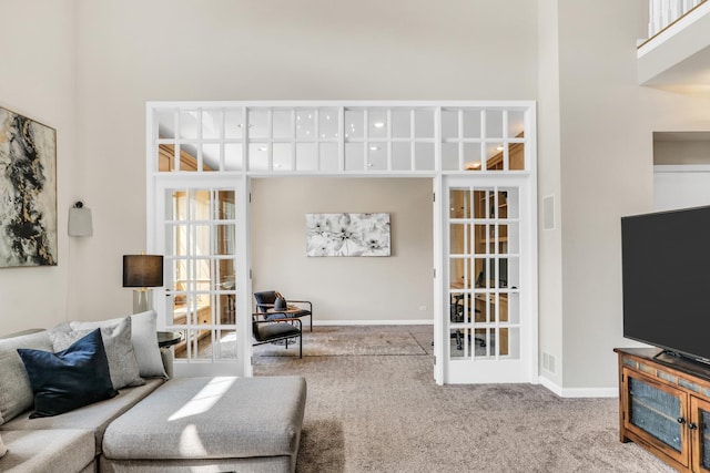 carpeted living room with a high ceiling, baseboards, and french doors