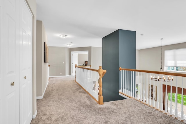 hallway with a chandelier, carpet floors, and baseboards
