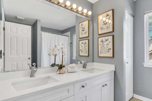bathroom featuring double vanity and baseboards
