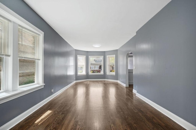 1235 N Mason Ave, Chicago, IL 60651 - spare room with arched walkways, plenty of natural light, wood finished floors, and baseboards