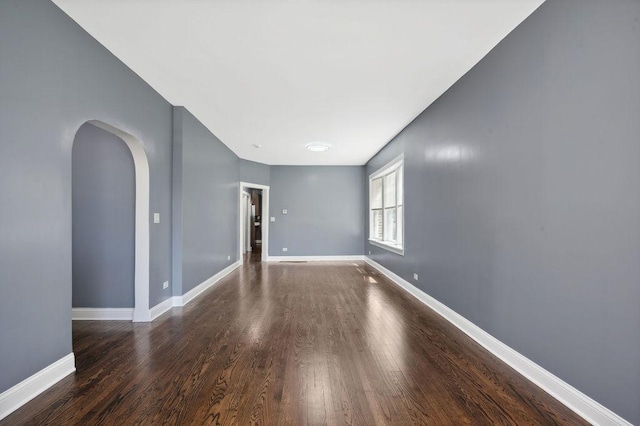 1235 N Mason Ave, Chicago, IL 60651 - empty room featuring arched walkways, wood finished floors, and baseboards